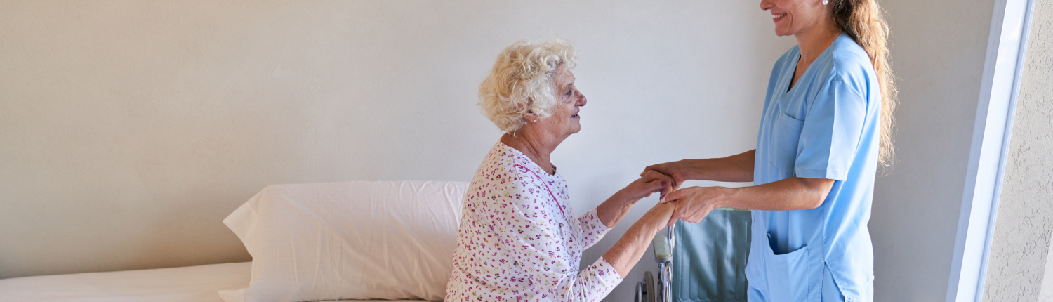 Fürsorgliche Krankenschwester hilft Seniorin beim Aufstehen